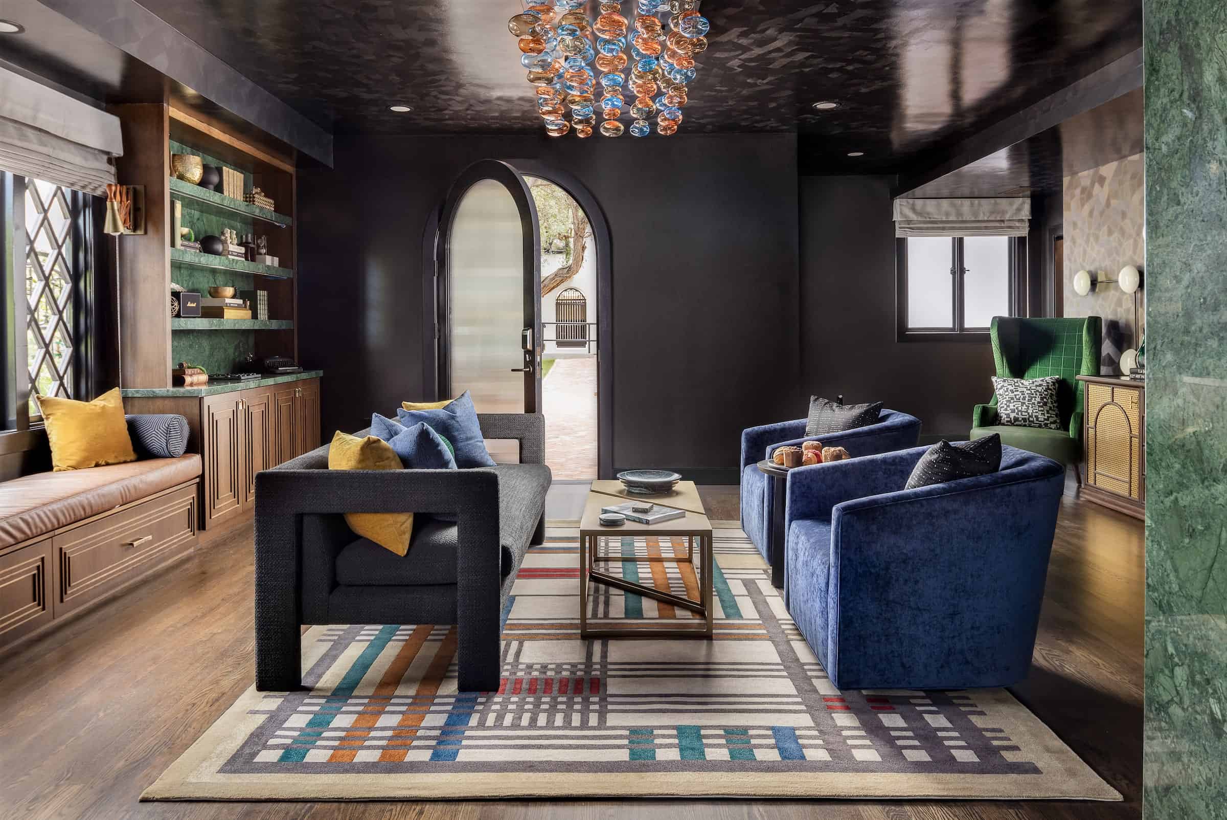 Stylish hotel lounge with blue velvet chairs, modern décor, patterned rugs, and arched doorway creating a cozy, upscale atmosphere