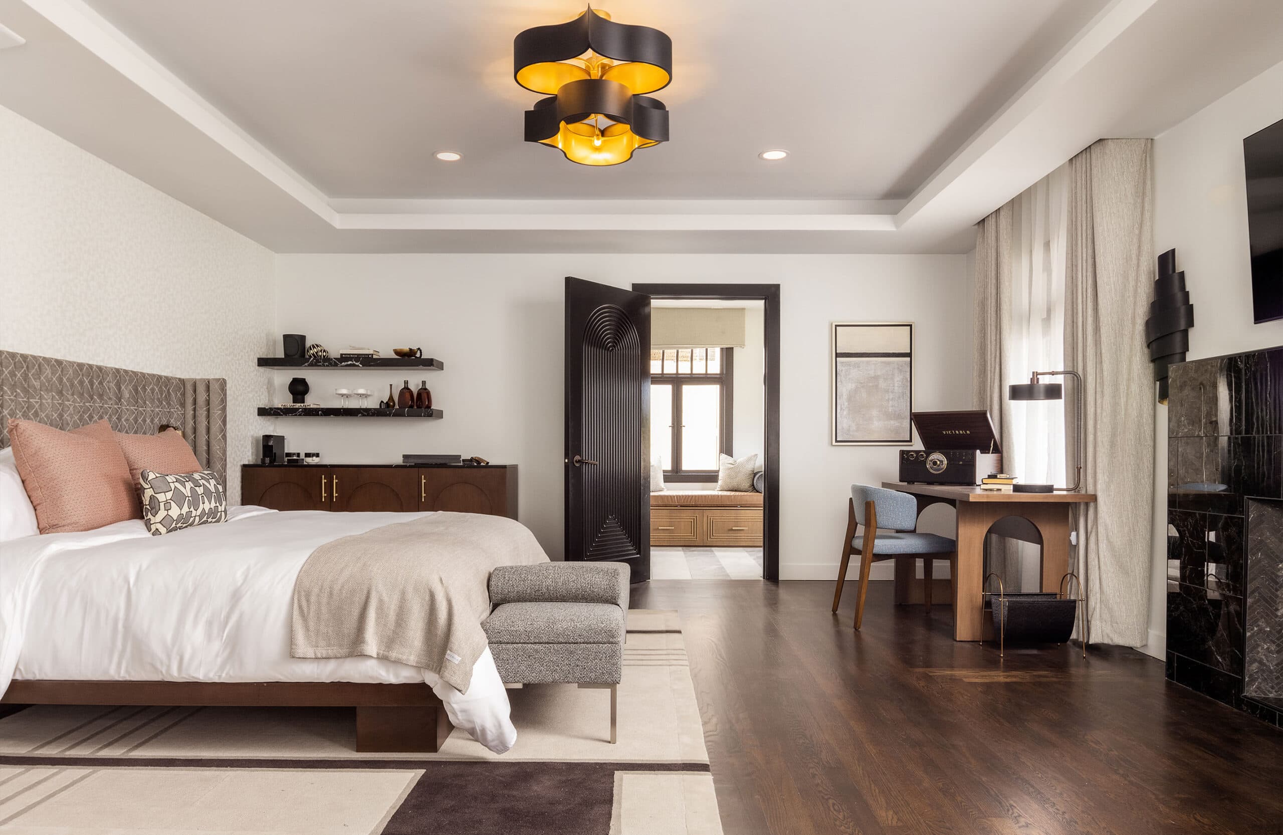 Spacious modern bedroom with a large upholstered bed, hardwood floors, and a stylish seating area.