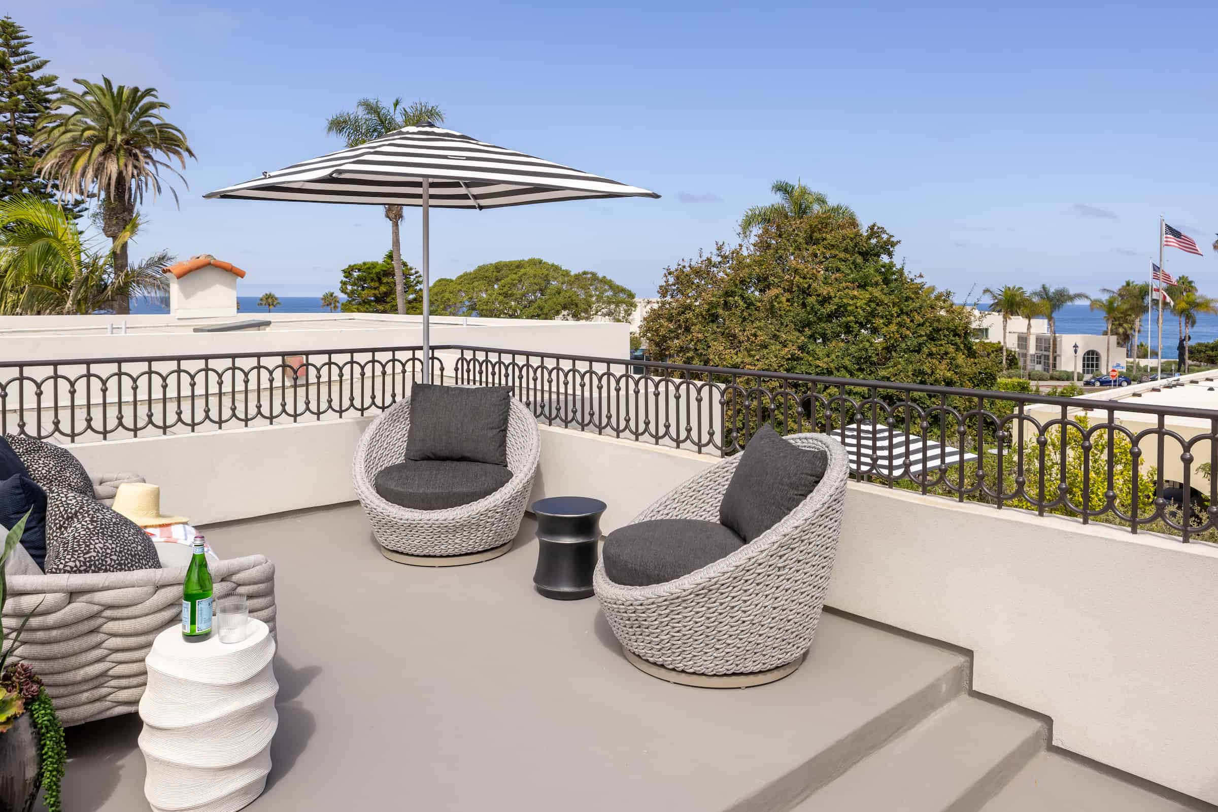 Rooftop terrace with modern outdoor seating, round lounge chairs, and city views under a clear sky.