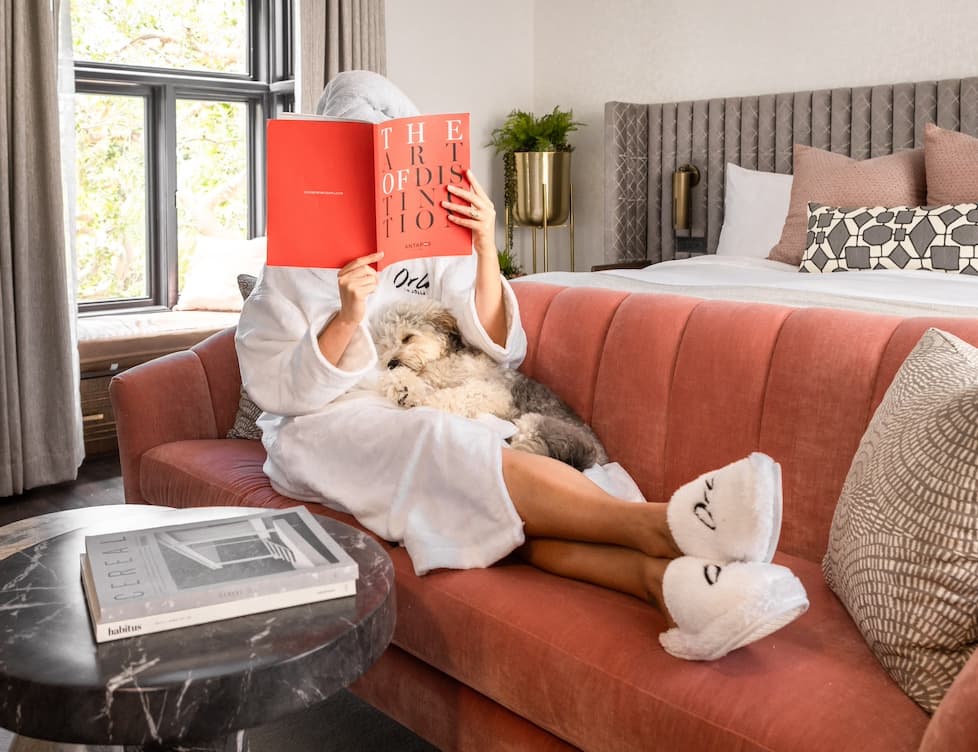 Puppy sleeping on the lap of a person wearing a bath robe and reading a book