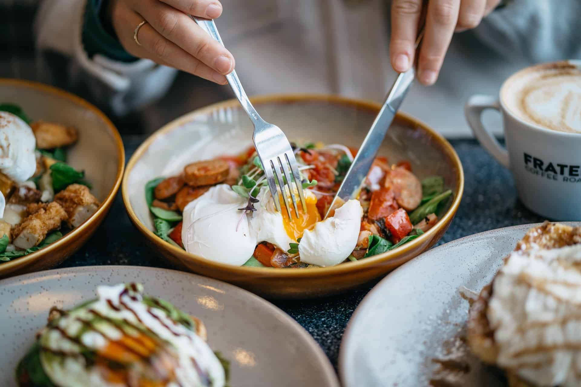 Fork and knife cutting into breakfast bowl