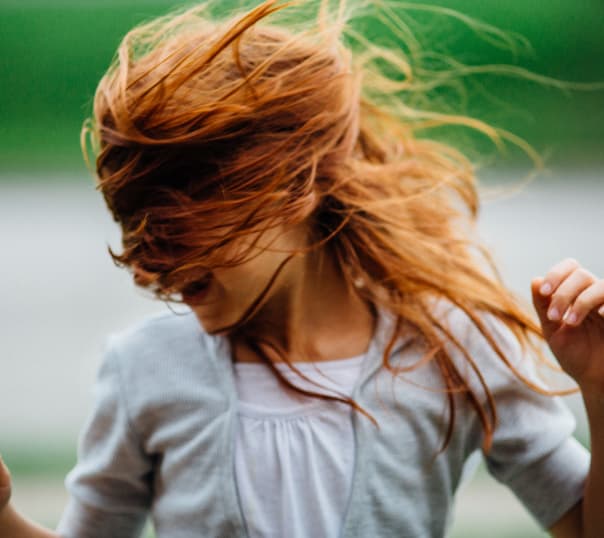 with running with the wind in her hair making it cover her face .