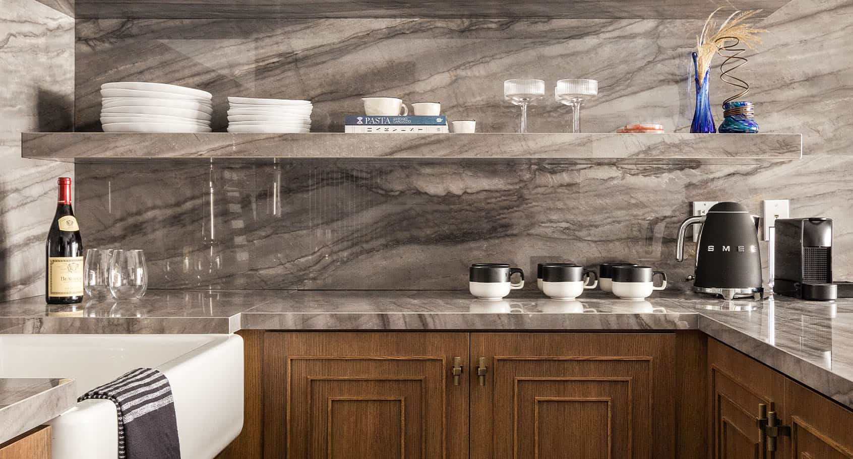 Modern in-room kitchenette with marble backsplash, wood cabinetry, and thoughtfully curated amenities