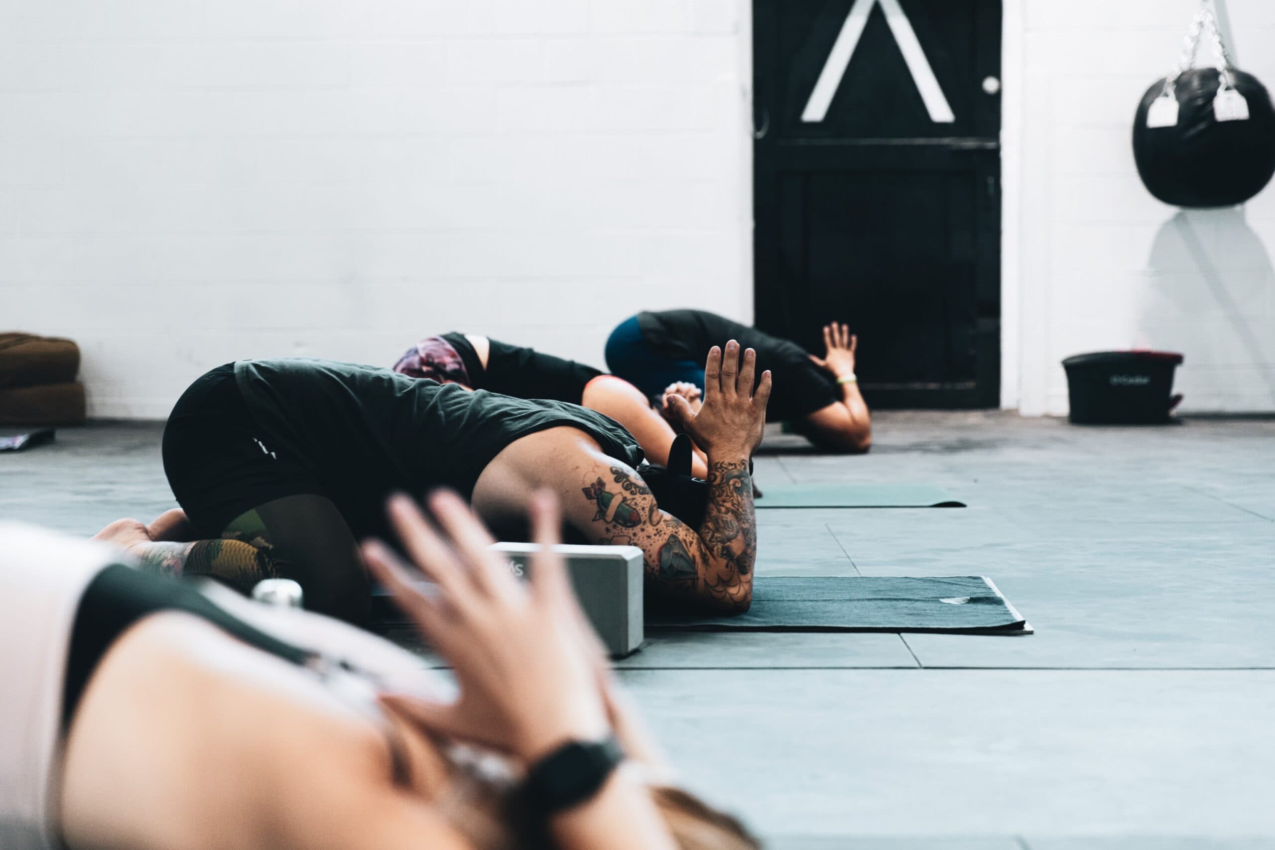 Group of people stretching on yoga mats during a fitness or wellness class in a modern studio