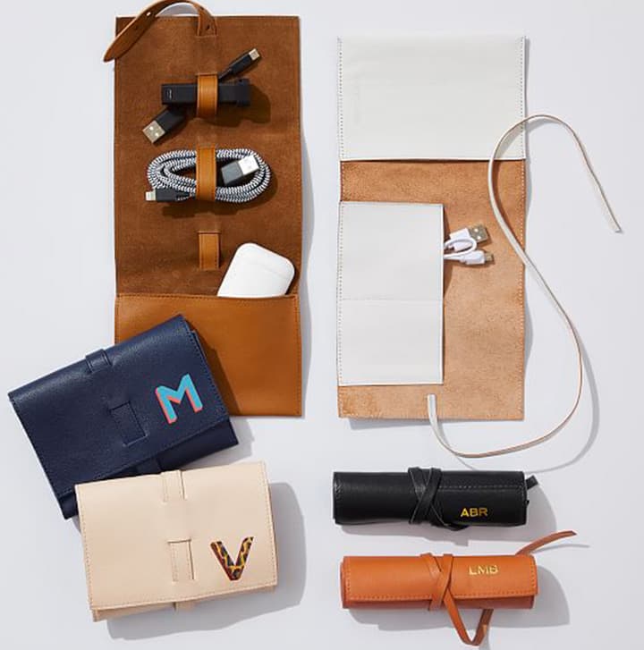 Leather travel organizers and pouches with charging cables, wallet, and accessories arranged in a flat lay for modern travel essentials