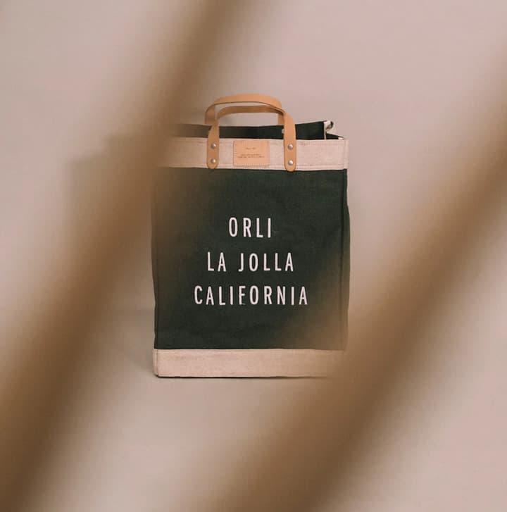 Canvas tote bag with leather handles printed with “Orli La Jolla California,” displayed against a soft neutral background
