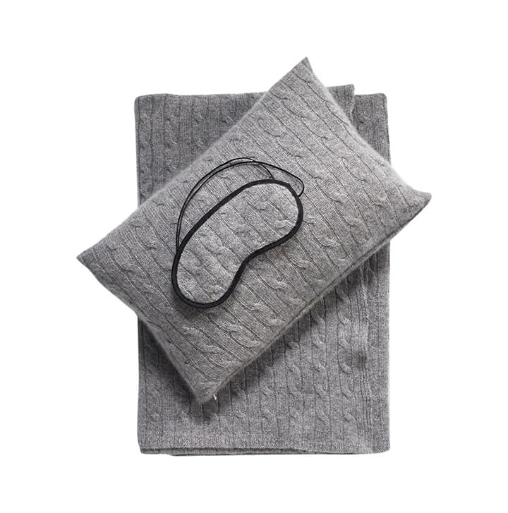 Gray quilted sleep mask resting on a matching textured fabric pouch for comfortable light-blocking rest