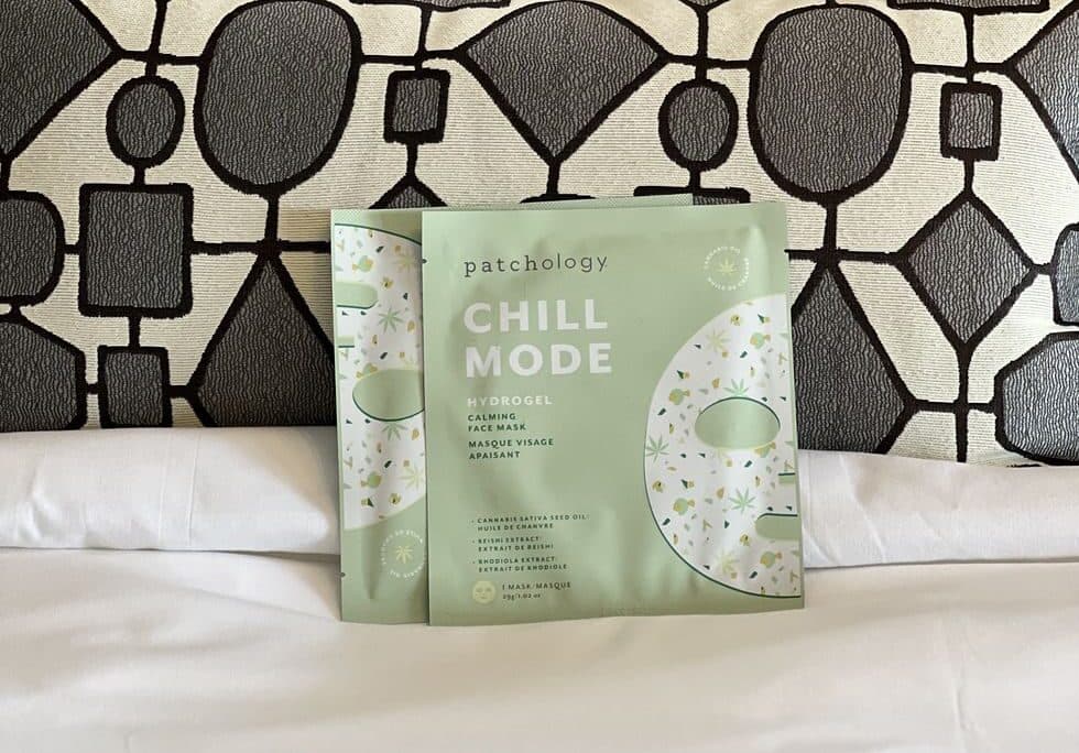 Patchology Chill Mode eye gel patches packaging displayed on a bed with patterned pillows for a relaxing skincare aesthetic