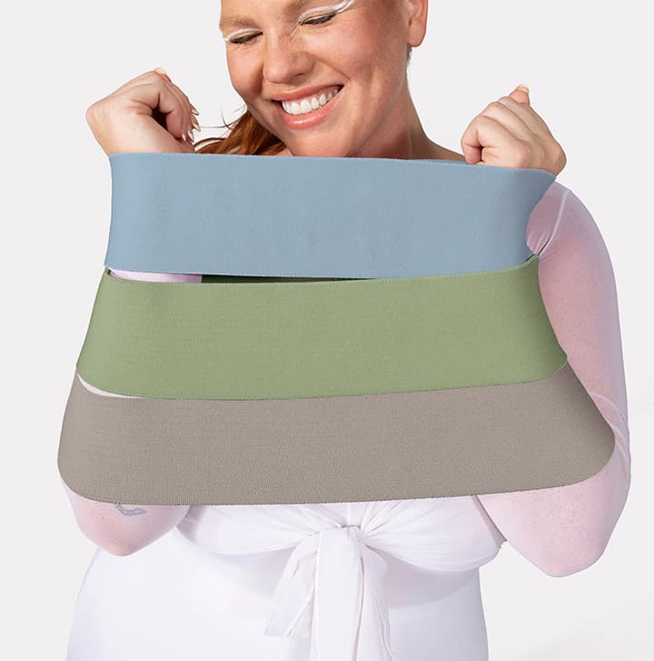 Smiling woman holding three stretch resistance bands in blue, green, and taupe for fitness and strength training
