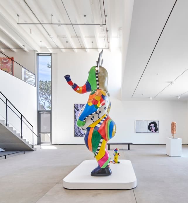 Colorful abstract elephant sculpture displayed in a modern art museum gallery with high ceilings.