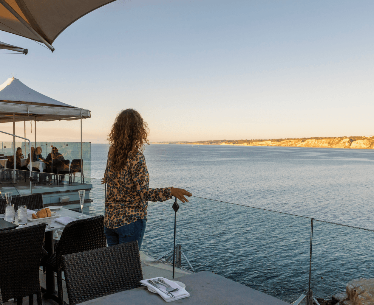 Guest standing on an oceanview restaurant terrace looking out over the coastline