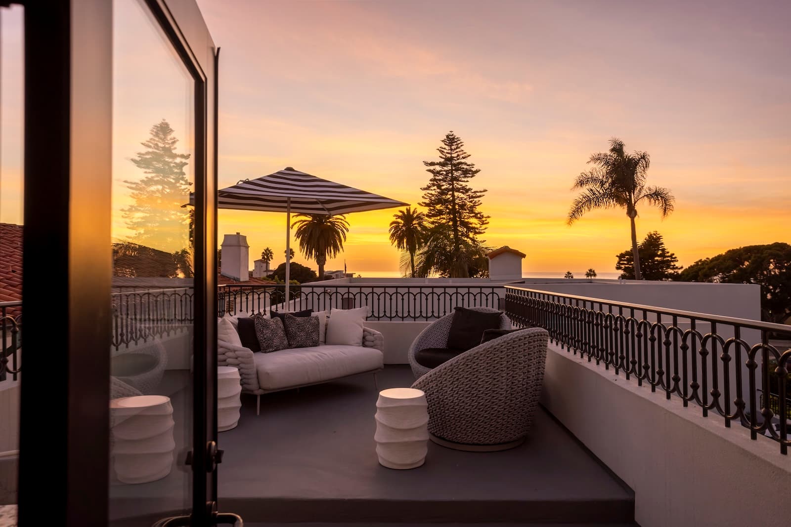 Outdoor terrace with lounge seating overlooking palm trees at sunset
