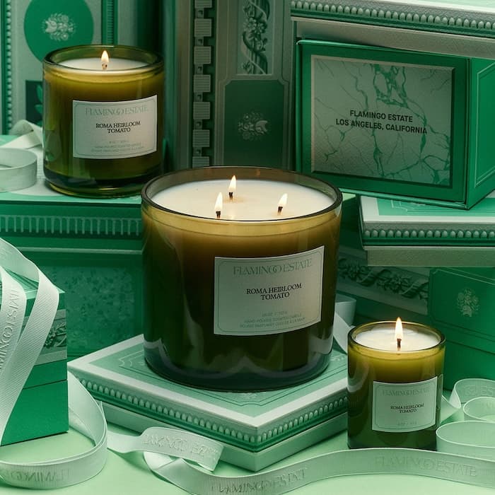 Luxury green glass scented candles with lit wicks displayed on elegant gift boxes and ribbons in a premium home décor setting