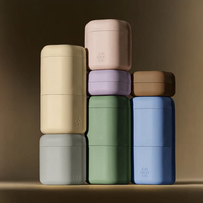Stacked pastel-colored reusable toiletry containers arranged in a minimalist display for sustainable travel and skincare storage