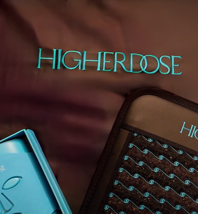 Close-up of HighERDose branding on wellness products, featuring a heated infrared mat and control device arranged on a soft fabric surface.