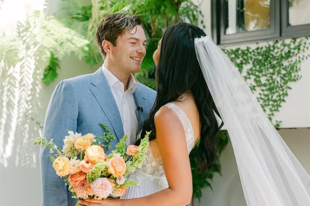 Bride and groom sharing a joyful moment outdoors, holding a colorful bridal bouquet during an elegant garden wedding ceremony.