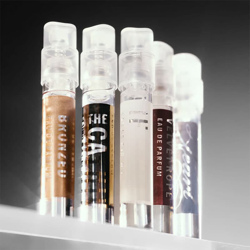Luxury fragrance sampler vials displayed on a shelf, featuring premium Eau de Parfum scents in minimalist glass spray bottles.