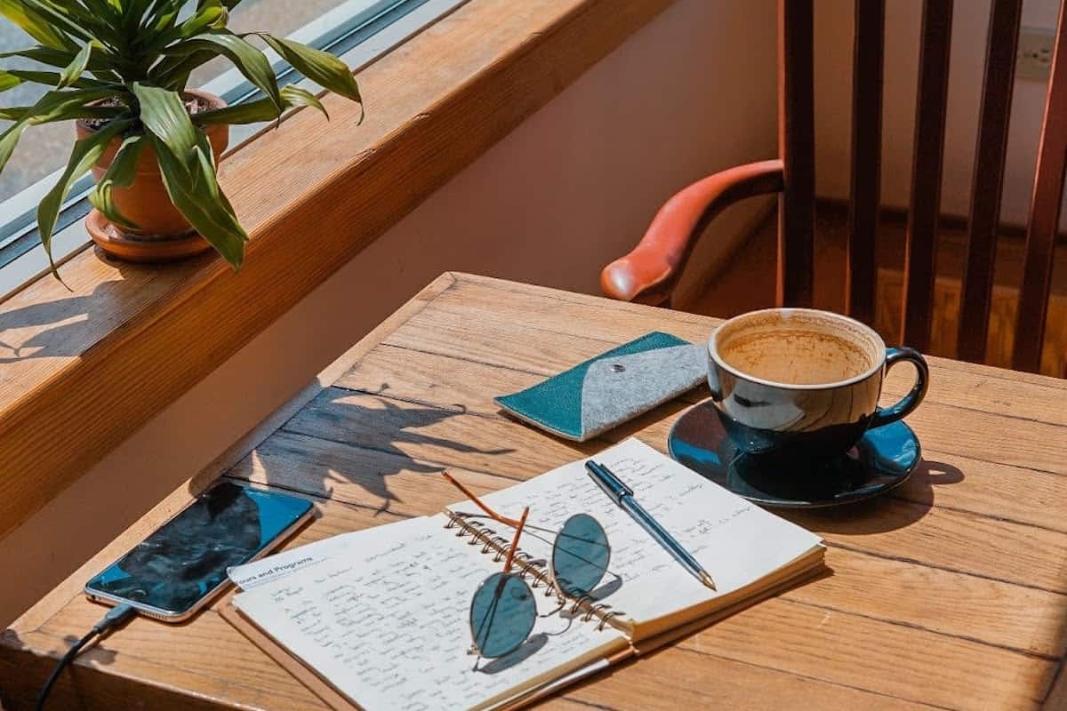 Cafe table with phone, journal, sunglasses and coffee mug