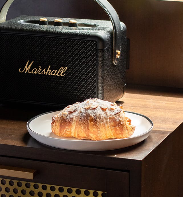 A croissant and a Marshall speaking on a nightstand at Orli La Jolla