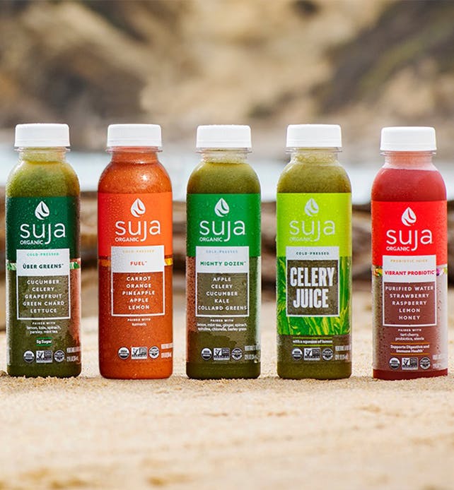 Assortment of Suja drinks standing next to each on a table